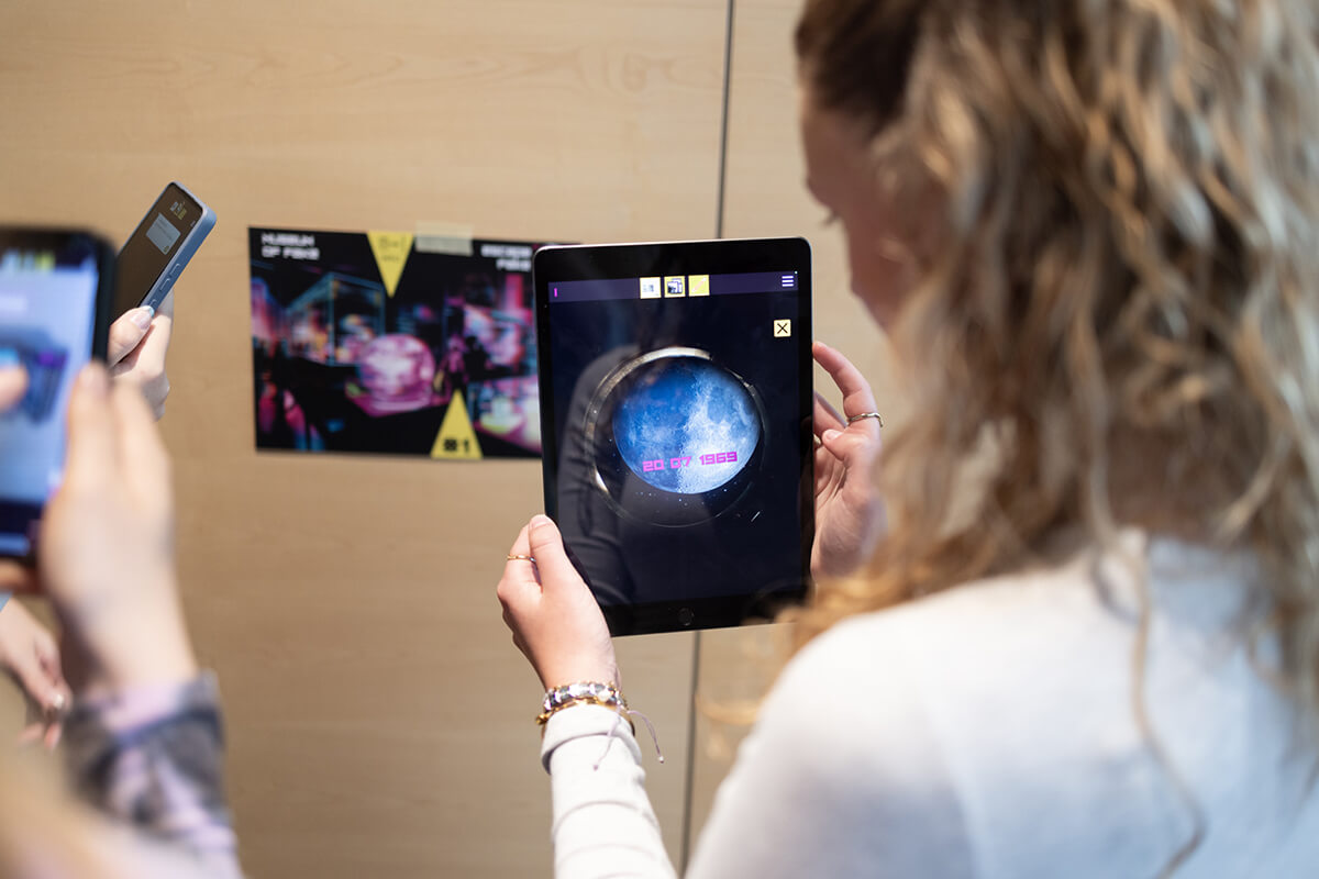 Schülerin spielt AR-Game "Museum of Fake" von Polycuar, Blick über ihre Schulter auf Tablet